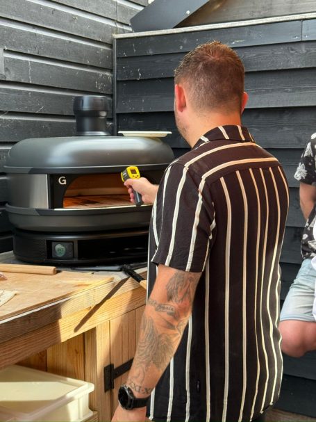 Man in gestreepte shirt meet de temperatuur van een oven.